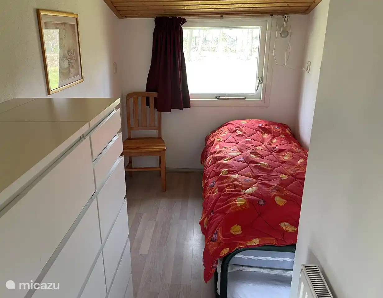 In deze kleine slaapkamer staat een bed met onderschuifbed (80 cm breed). In de ladenkast op de voorgrond is er ruimte om kleding op te bergen. Ook ligt er wat kinderspeelgoed en spelllen.