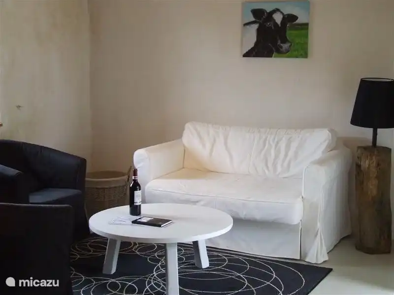 De huiskamer van de koeienstal geheel in stijl in de kleuren zwart/wit met slaapbank voor e.v.t. de 5e en 6e persoon.Over de hele beneden verdieping is vloerverwarming van aardwarmte.