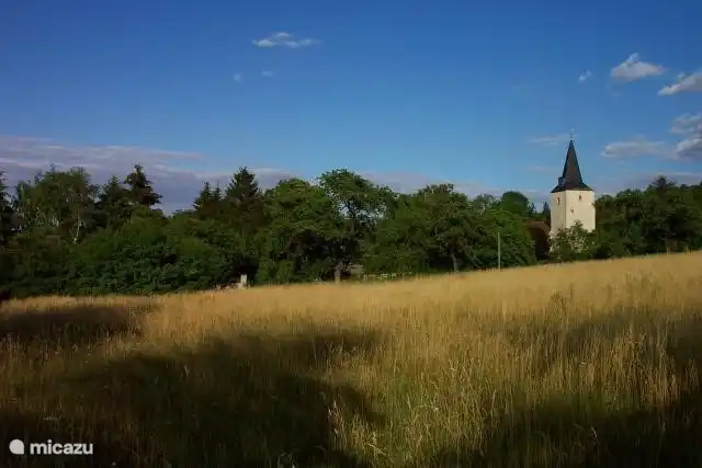 Das Haus liegt hinter den Bäumen. Kirche ist rechts