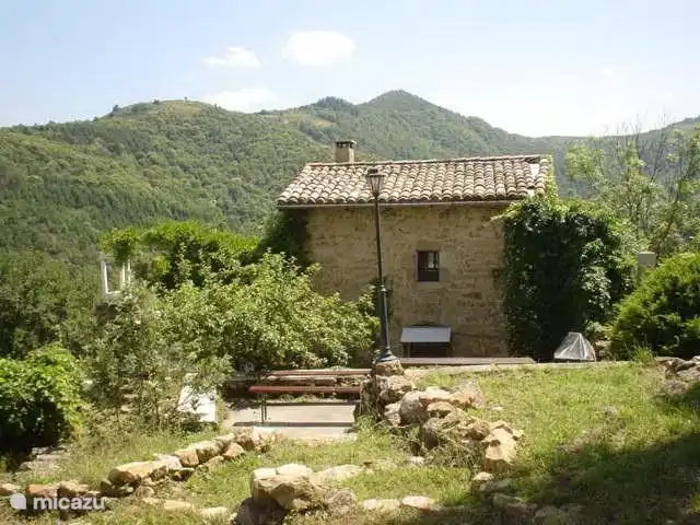 Mitten im Sommer: Vorderansicht von l'Amande. Das Haus ist umgeben von Bergen.