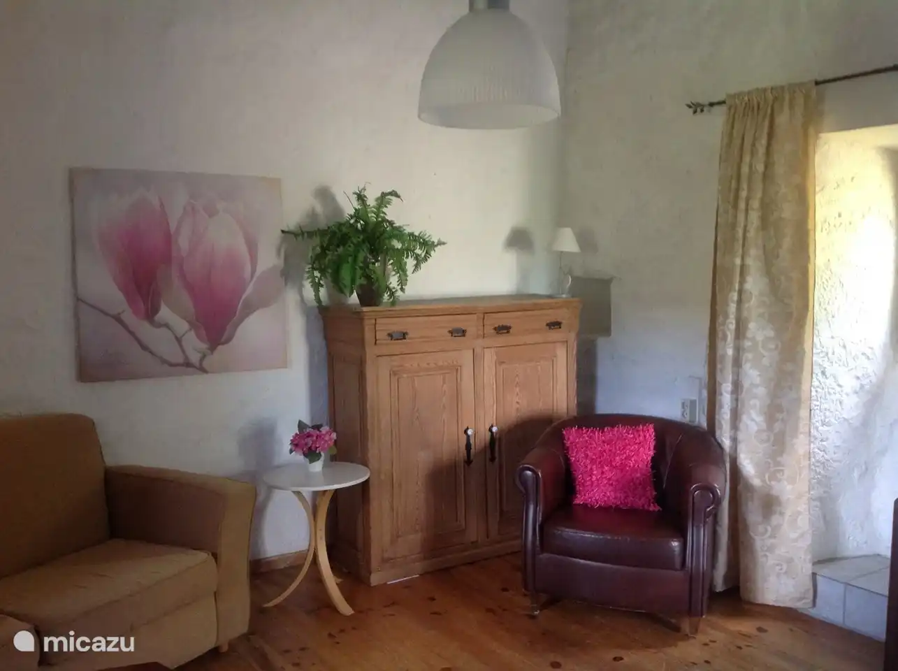 Eine begehbare Ecke des Wohnzimmers mit romantischem Holzofen und schöner Sitzecke, ein LED-Fernseher mit allen niederländischen Kanälen und eine Tür zur (2.) gefliesten oberen Terrasse mit herrlichem Blick über die Berge.