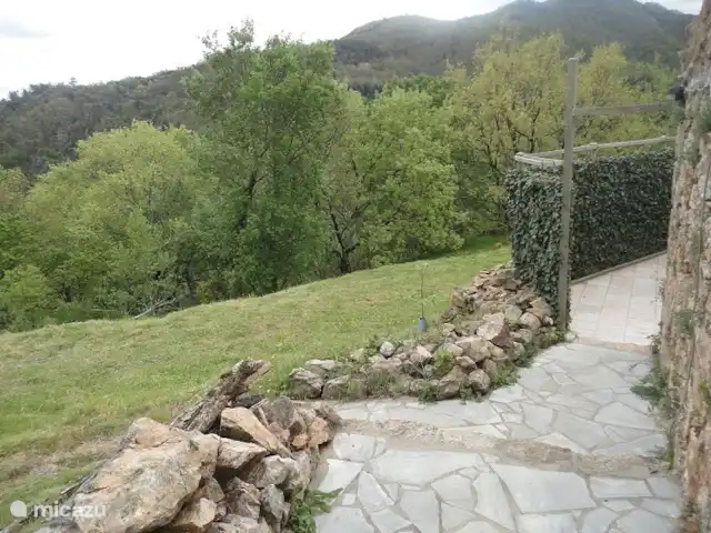 La basse Maza - L'Amande | France, Ardèche, Gluiras - maison de vacances Chemin dallé devant la maison avec éclairage nocturne, traverse une porte verrouillable menant à la terrasse inférieure avec pelouse derrière la maison. Toute la cour arrière est entourée de verdure et offre beaucoup d'intimité. Idéal pour les familles avec de jeunes enfants ou des animaux domestiques, car la terrasse peut être fermée.