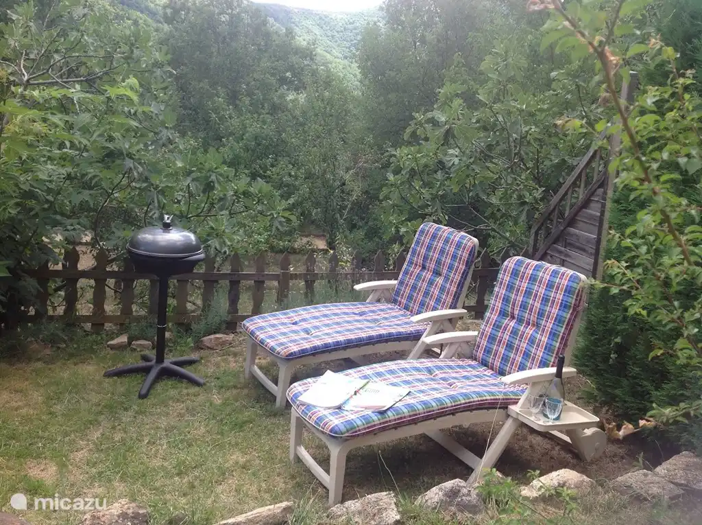 Liegewiese mit Sonnenliegen und Grill.