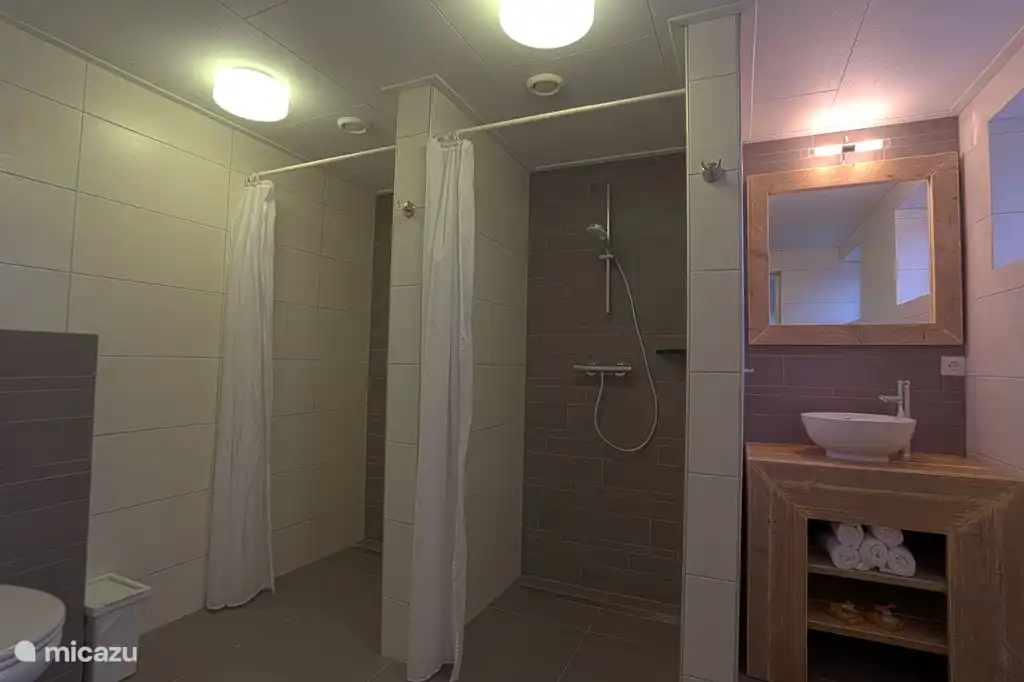 Badezimmer mit 2 Duschen, Waschbecken und Toilette.