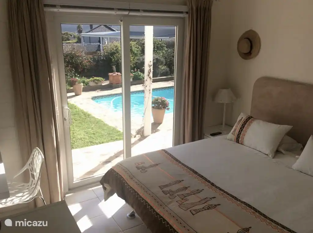 Schlafzimmer mit angrenzendem Badezimmer. Öffnen von Türen zum Garten und Pool.