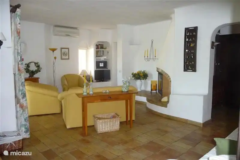 Das geräumige Wohnzimmer mit Kamin und Klimaanlage. Links und rechts ein Durchgang zu den Schlafzimmern und Bädern.