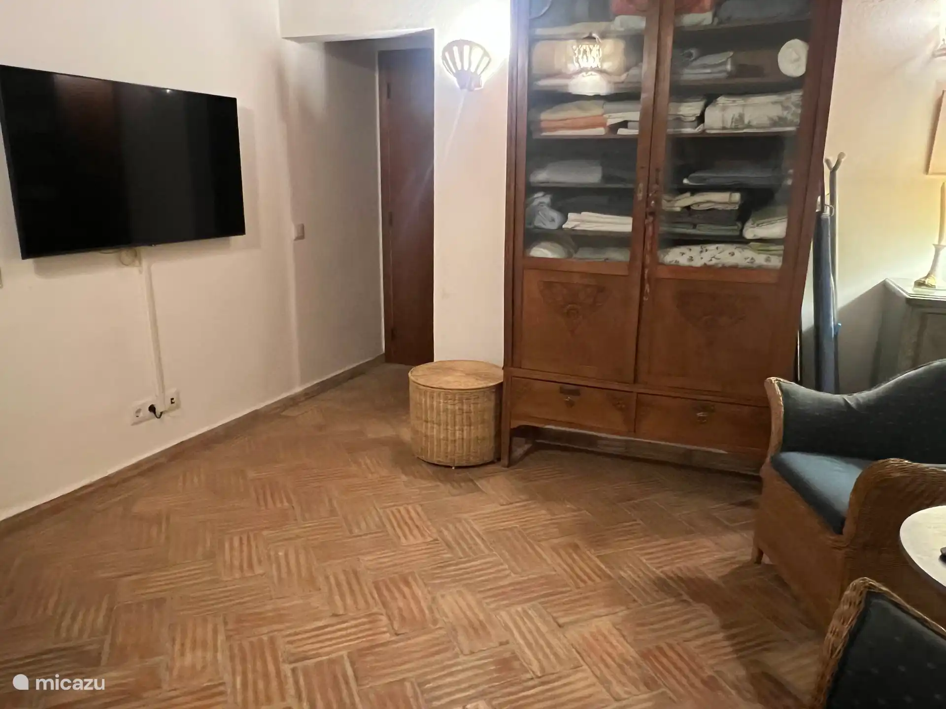 Vom Sitzbereich im Fernsehzimmer aus ist es gut, fernzusehen. Rechts vom Fernseher befinden sich der Zugang zur Toilette und zum Badezimmer. Links vom Fernseher ist der Eingang zum Wohnzimmer außerhalb des Bildes.