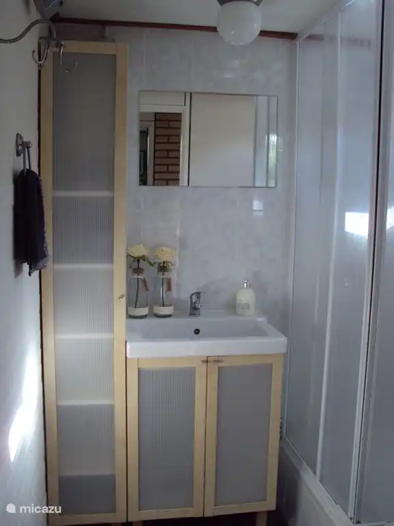 The bathroom has a shower and is equipped with hand shower. There is a toilet, sink and storage cabinet available.