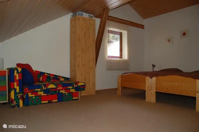Ein sehr geräumiges Dachzimmer mit 2 Einzelbetten 90x200, einem Zustellbett 90x200, einem bunten Kinderbett und einem Campingbett. In diesem Dachzimmer gibt es auch einige Kinderspielzeuge.
