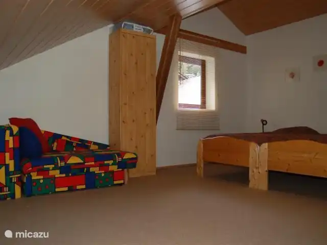 Maison Bergzicht | Allemagne, Sauerland, Willingen - appartement Une chambre mansardée très spacieuse avec 2 lits simples de 90x200, un lit d'appoint de 90x200, un lit bébé aux couleurs vives et un lit de camp. Il y a aussi des jouets pour enfants dans cette chambre mansardée.