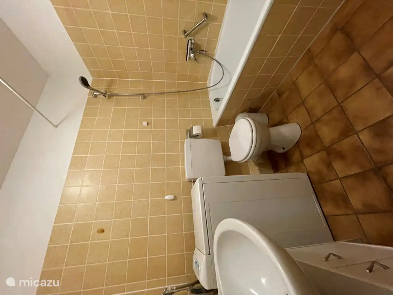 Der Sanitärbereich der Wohnung: ein Badezimmer mit Toilette, Waschbecken und Badewanne/Dusche. Es gibt auch eine Waschmaschine im Badezimmer.