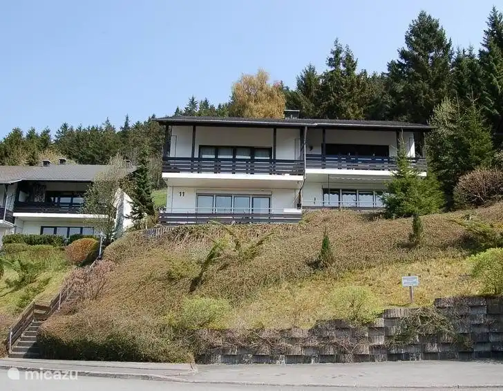 Die Wohnung (oben rechts) von der Straße aus gesehen. Auf der Straßenseite befindet sich ein Stellplatz für Ihr Auto und über die Treppe links auf dem Foto gelangen Sie bis zur Haustür der Wohnung.
