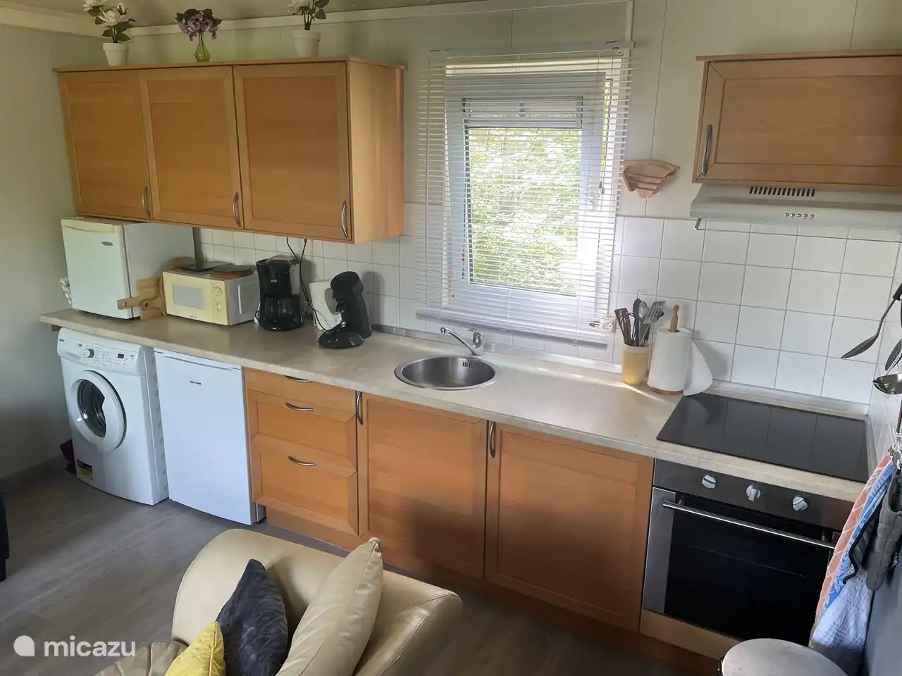 Die Wohnküche erstreckt sich über die gesamte Länge des Ferienhauses. Neben dem Kühlschrank mit eingebautem Gefrierfach gibt es eine zusätzliche Kühlbox, einen Geschirrspüler und eine Waschmaschine.