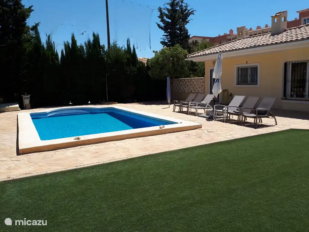 Swimmingpool mit Terrasse und Sonnenliegen.