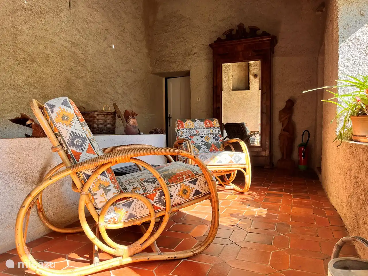 Gemütlicher überdachter Sitzbereich mit Blick auf den Innenhof und die Hügel. Auf der linken Seite befindet sich der Eingang zum Elysium.