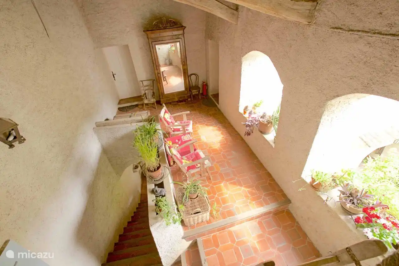 Die überdachte Terrasse mit Sesseln und Blick über den Innenhof auf die Hügel.