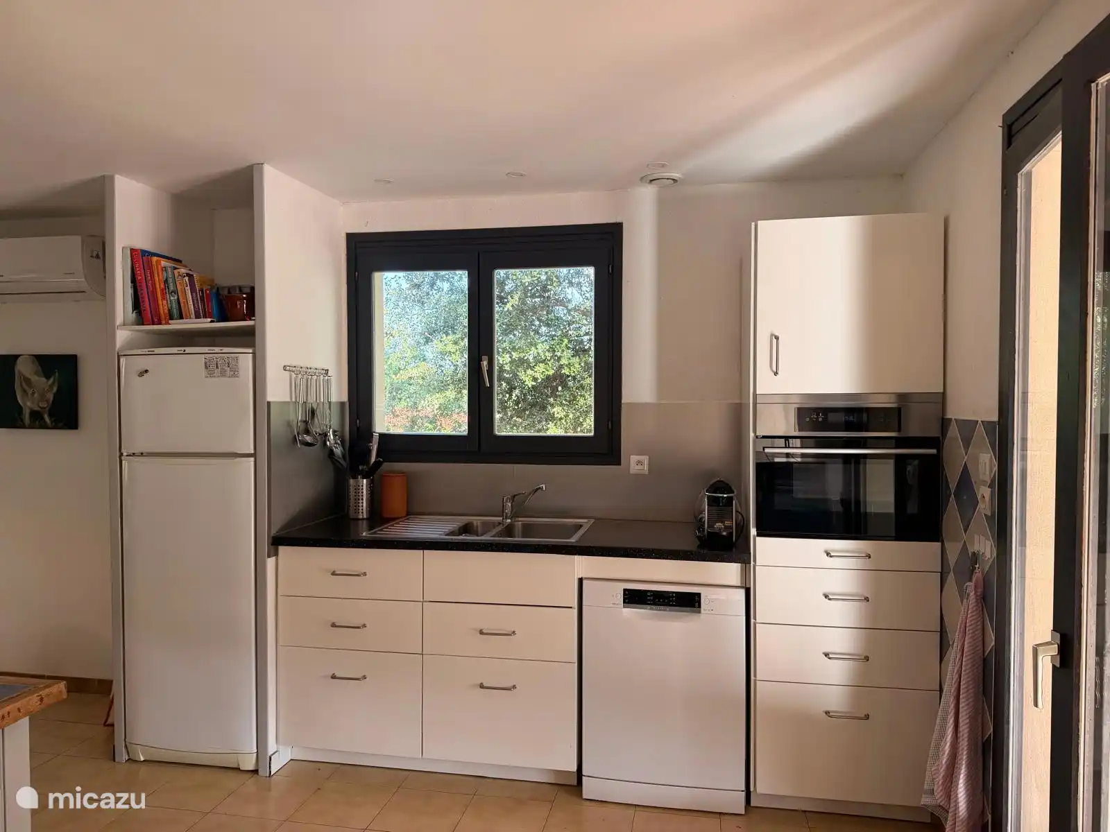 Keuken met ovenmagnetron, koelkast, vriezer, vaatwasser en Nespresso apparaat. 