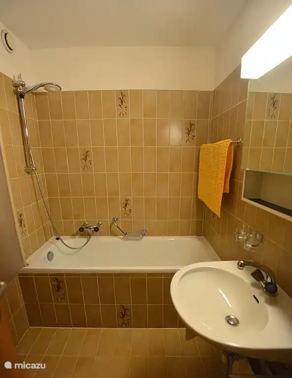 De badkamer met douche en ligbad.