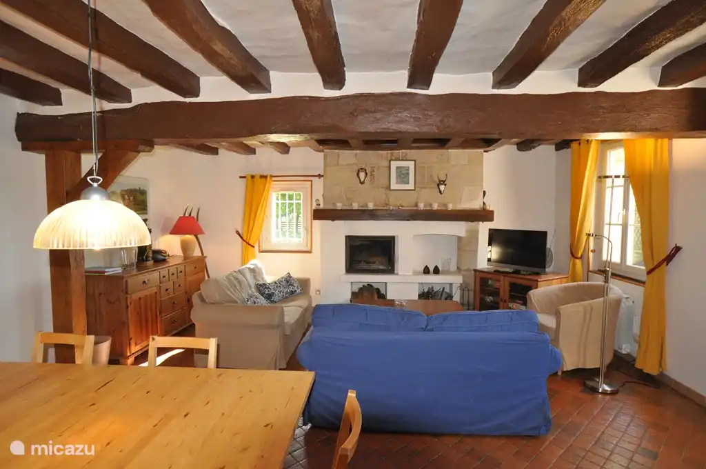 Cozy living room with fireplace, comfortable seating and a large dining table.