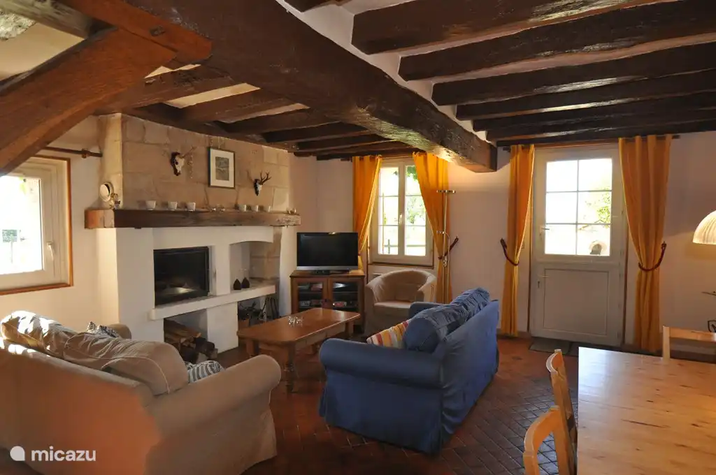 Cozy living room with fireplace, comfortable seating and a large dining table.