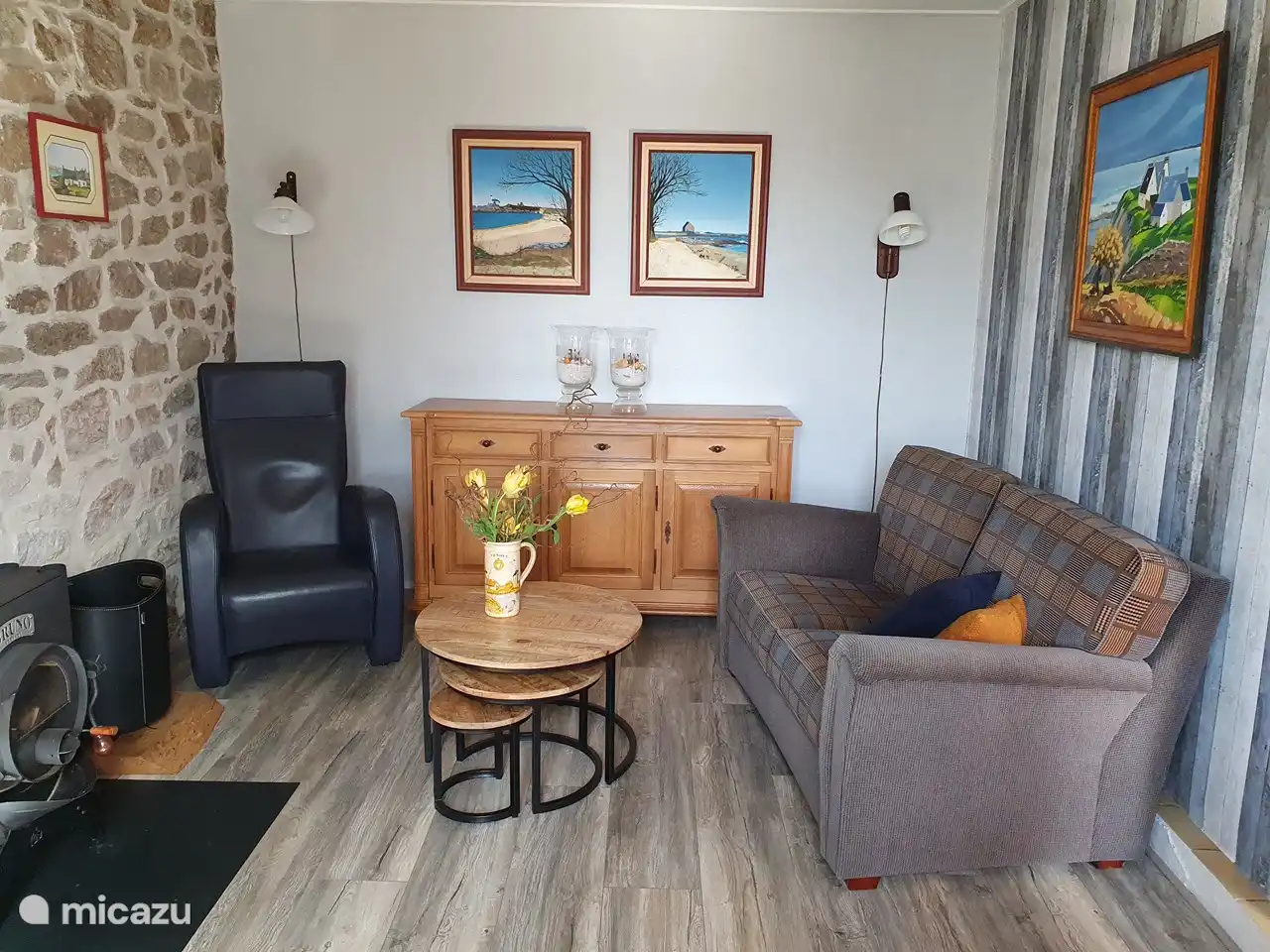 The living room with 2 two-seater sofas and an armchair. The dresser contains books, DVD movies and information about the area.