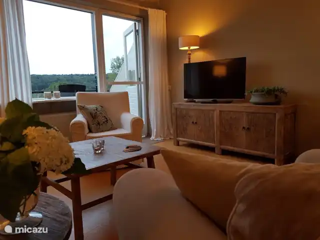 Buitenverblijf `t Herfse - 3 | Pays-Bas, Limbourg, Malines - ferme Une partie du coin salon avec vue. Le meuble TV contient des copies des plus beaux itinéraires à pied, à vélo et en voiture, des plans et des cartes, des conseils utiles pour les visiteurs du restaurant, de nombreuses informations sur toutes sortes de sites et d'événements et une pile de magazines (actuels).