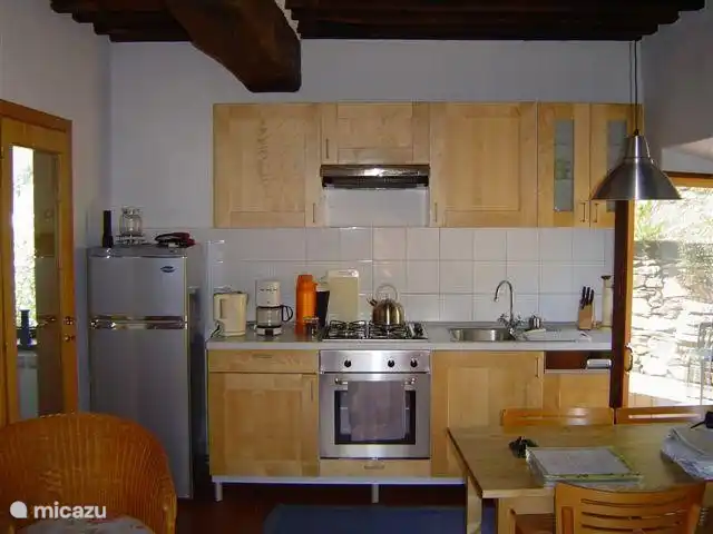 La sala de estar del anexo de la cocina está amueblada de manera ordenada y sobria. Adyacente se encuentra la terraza exterior de piedra natural y en una meseta más alta, a unos pocos escalones, se encuentra una terraza de césped donde se puede tomar el sol y disfrutar de la vista.