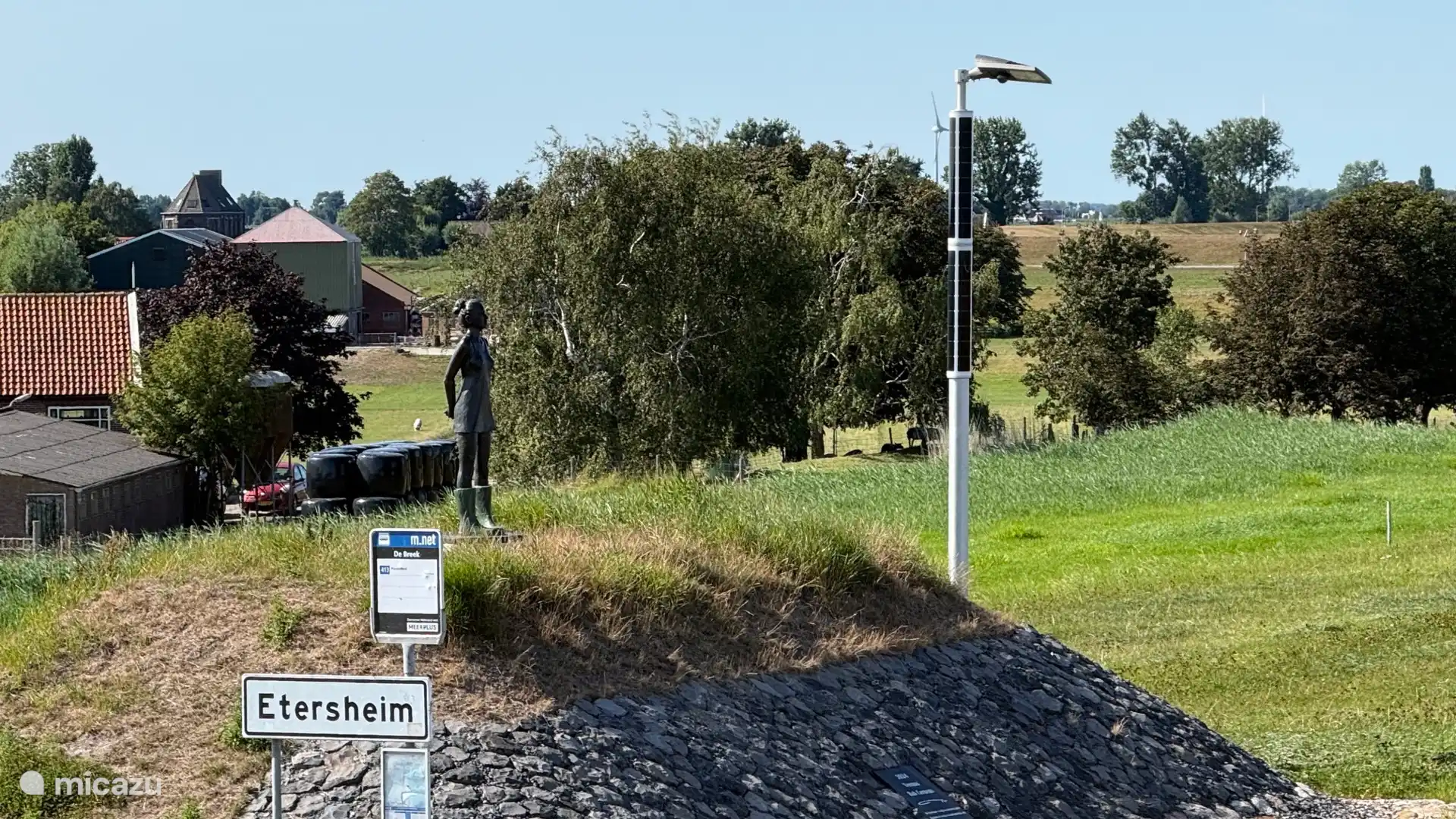 Meisje met laarzen, standbeeld op een stukje oude dijk;  kijkend naar het IJsselmeer