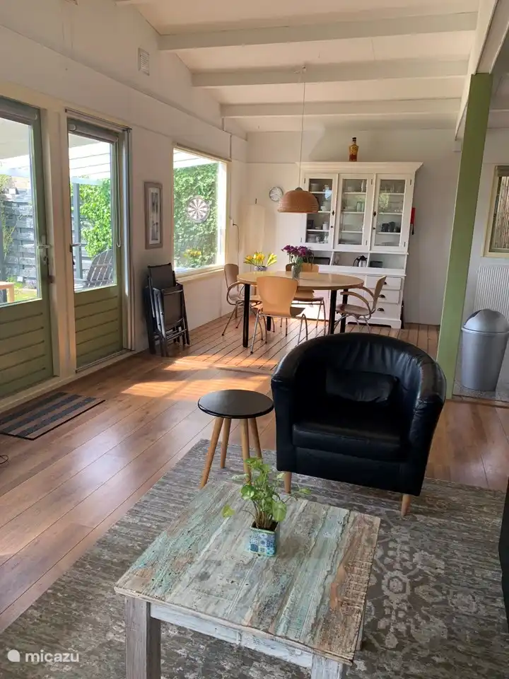 Sala de estar con puertas que dan a la terraza, mesa de comedor redonda y cocina abierta