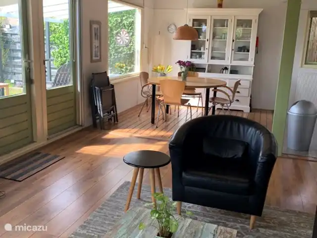 bungalow huren in Nederland, Noord-Holland, Schardam – Koggenbungalow Huiskamer met openslaande deuren naar de veranda, ronde eettafel en open keuken
