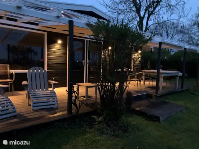 bungalow huren in Nederland, Noord-Holland, Schardam – Koggenbungalow Vanuit de tuin kijkend naar de veranda met luie stoelen