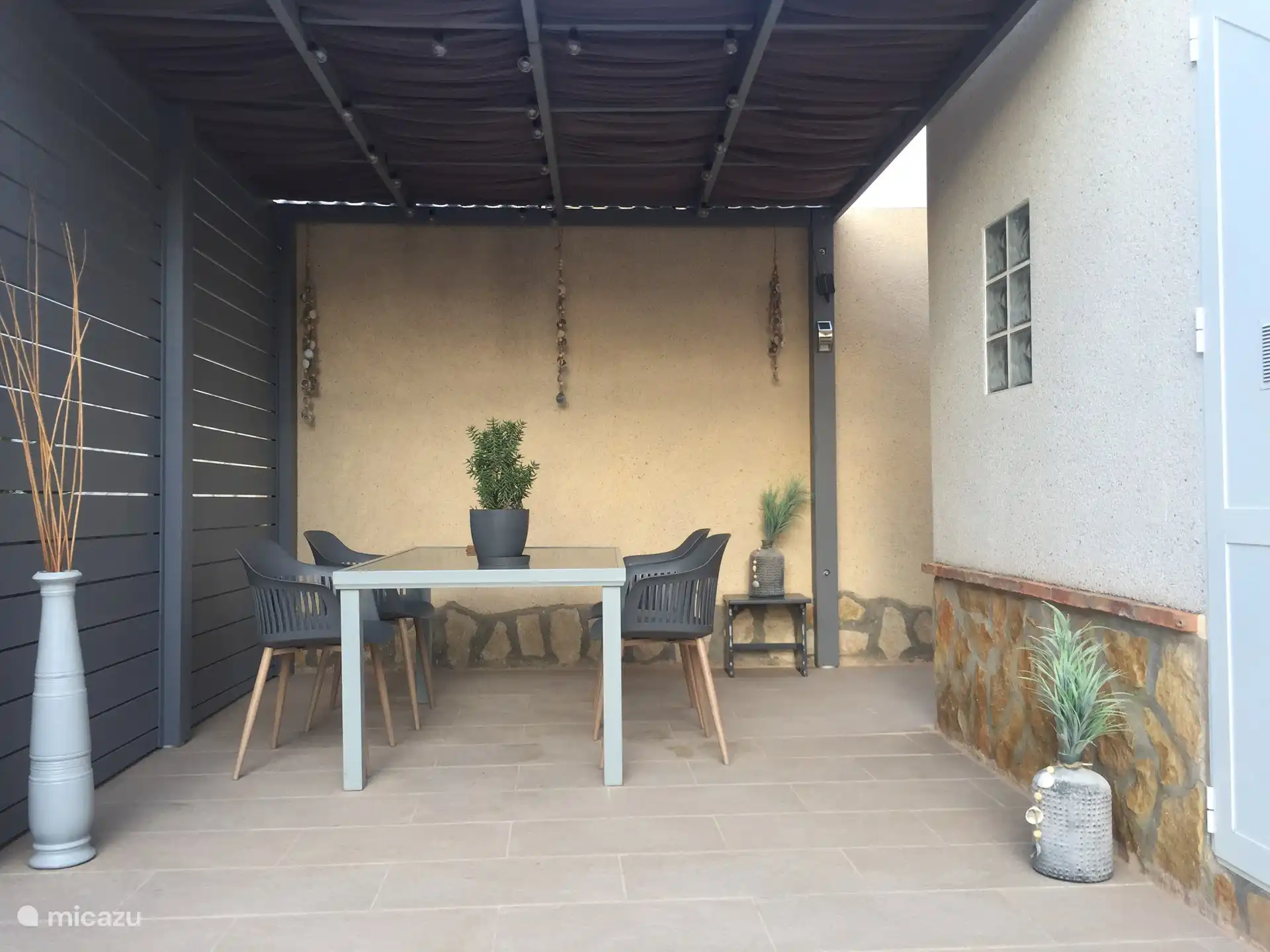 De overkapping achter in de tuin, met verlichting 