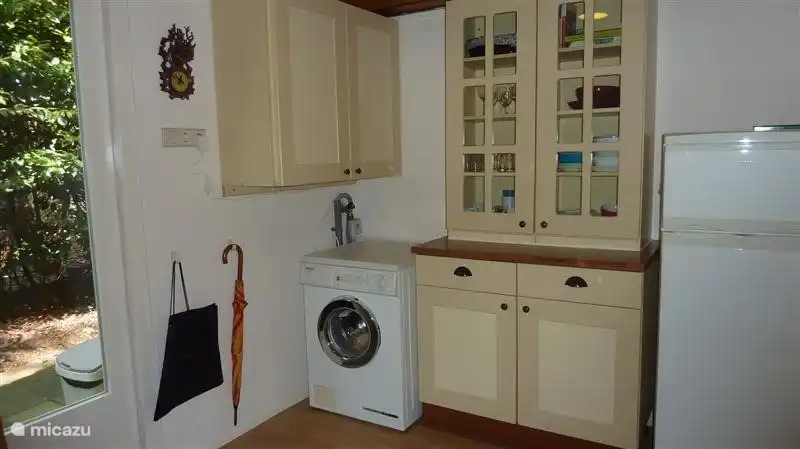 De bijkeuken met buffetkast, koelkast en wasmachine