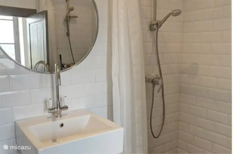 Gleiche Badezimmer aber von der anderen Seite. Die zweite Dusche ist im Spiegel sichtbar. Es gibt auch eine Toilette und ein Waschbecken und Handtuchtrockner.