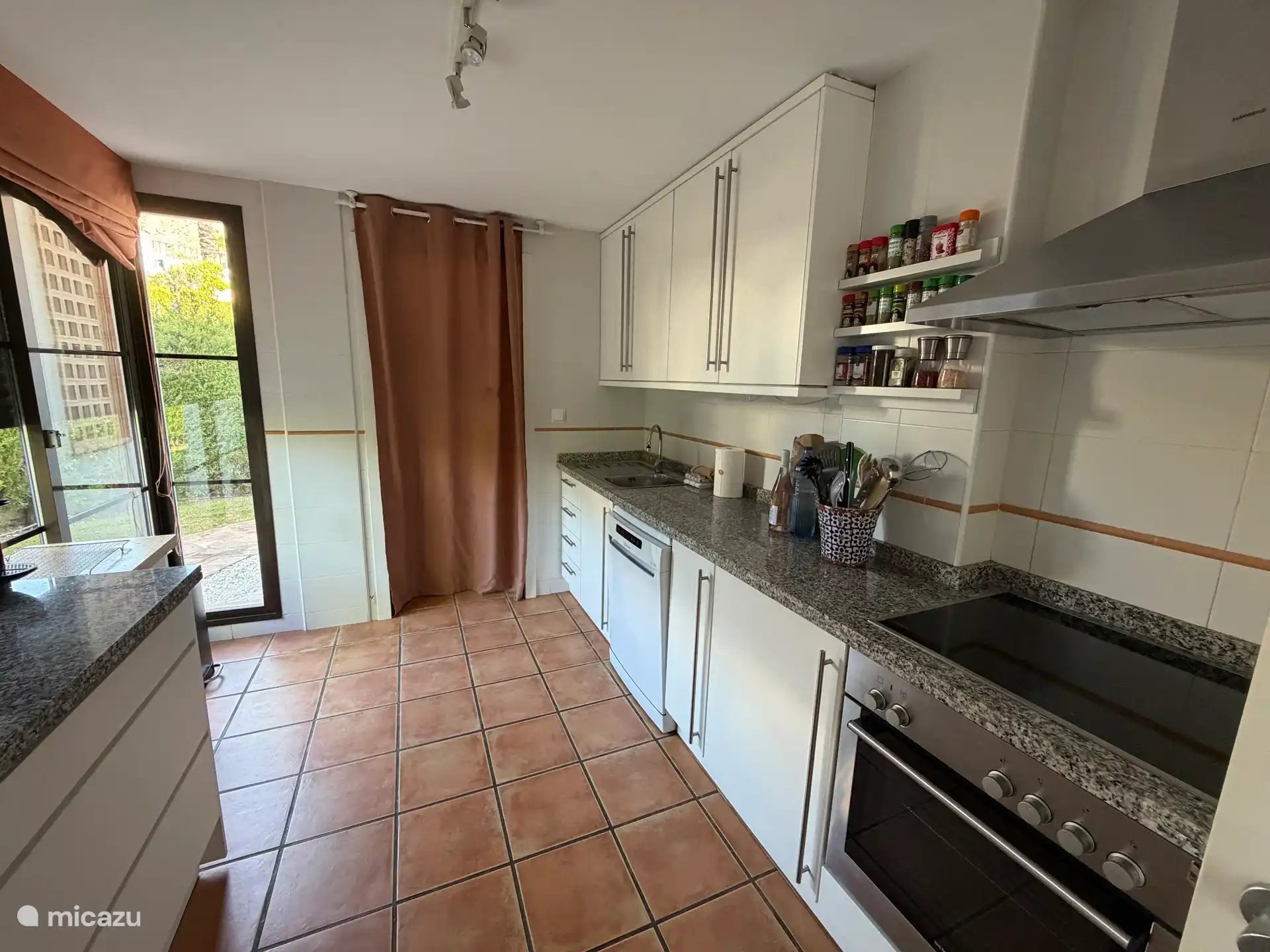Cocina con horno, placa, microondas, lavavajillas y nevera con compartimento separado para congelador.