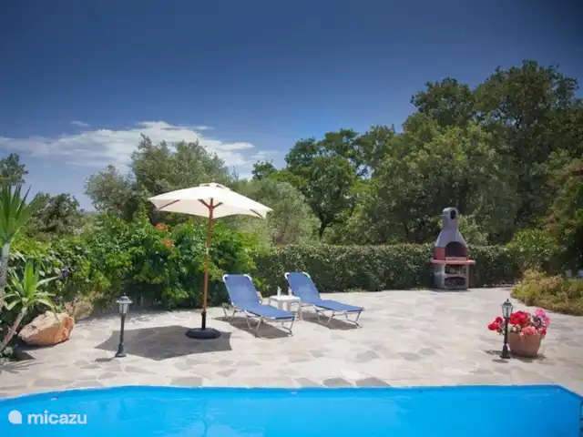 Villa Éléonore | Grèce, Crète, Prinès - villa Belle piscine avec transats, entourée de fleurs et d'une haie verte.