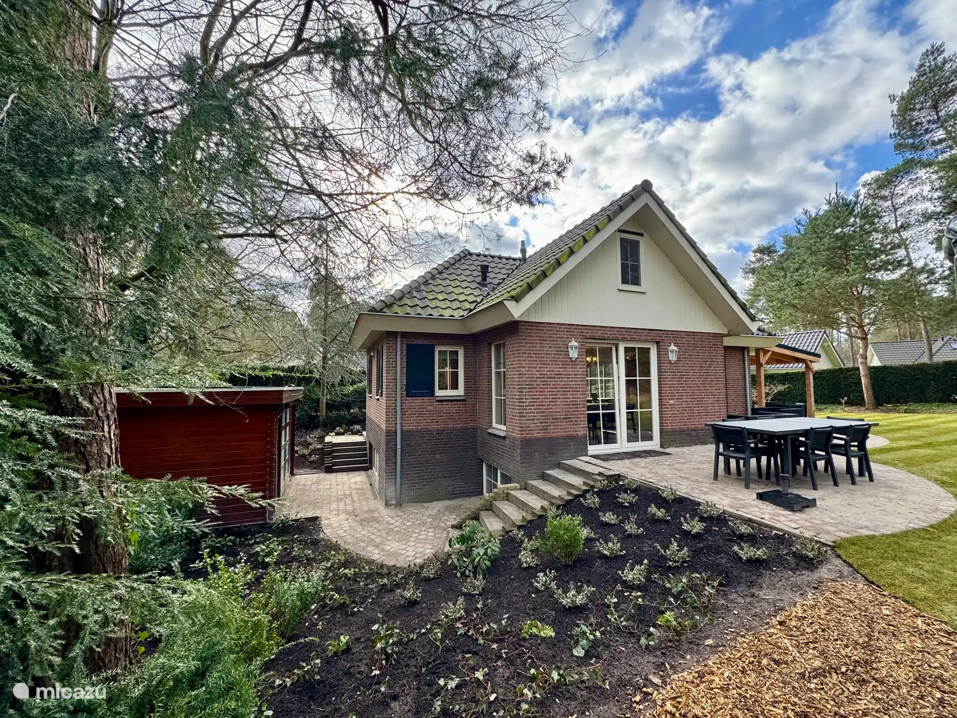 De achterzijde van de vakantiewoning met de houten berging.