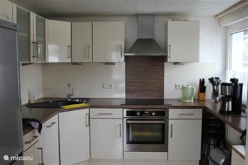 Onze moderne keuken met apparatuur zoals een oven, afzuigkap, koelkast en vrieskast en uiteraard een vaatwasser. Koken gaat op inductie. De speciale pannen staan in de keukenkastjes.