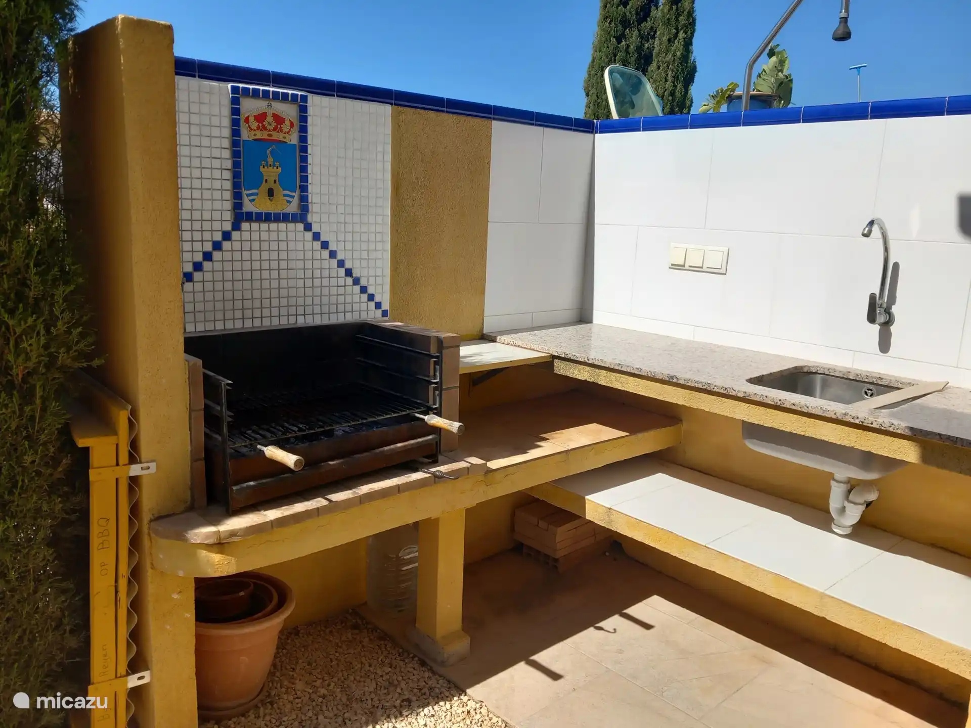 Buitenkeuken met BBQ, waarboven in mozaïek het wapen van Mazarrón is gemaakt. Er zijn stopcontacten, verlichting, rvs spoelbak en werkbladen.