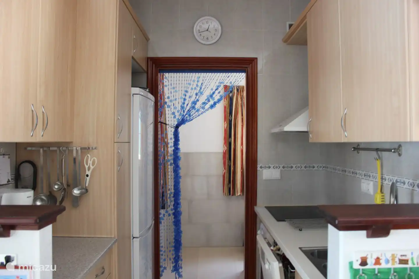 View from kitchen to utility room. The kitchen has 2 worktops, double sink, ceramic hob, extractor hood, fridge-freezer, coffee maker and dishwasher