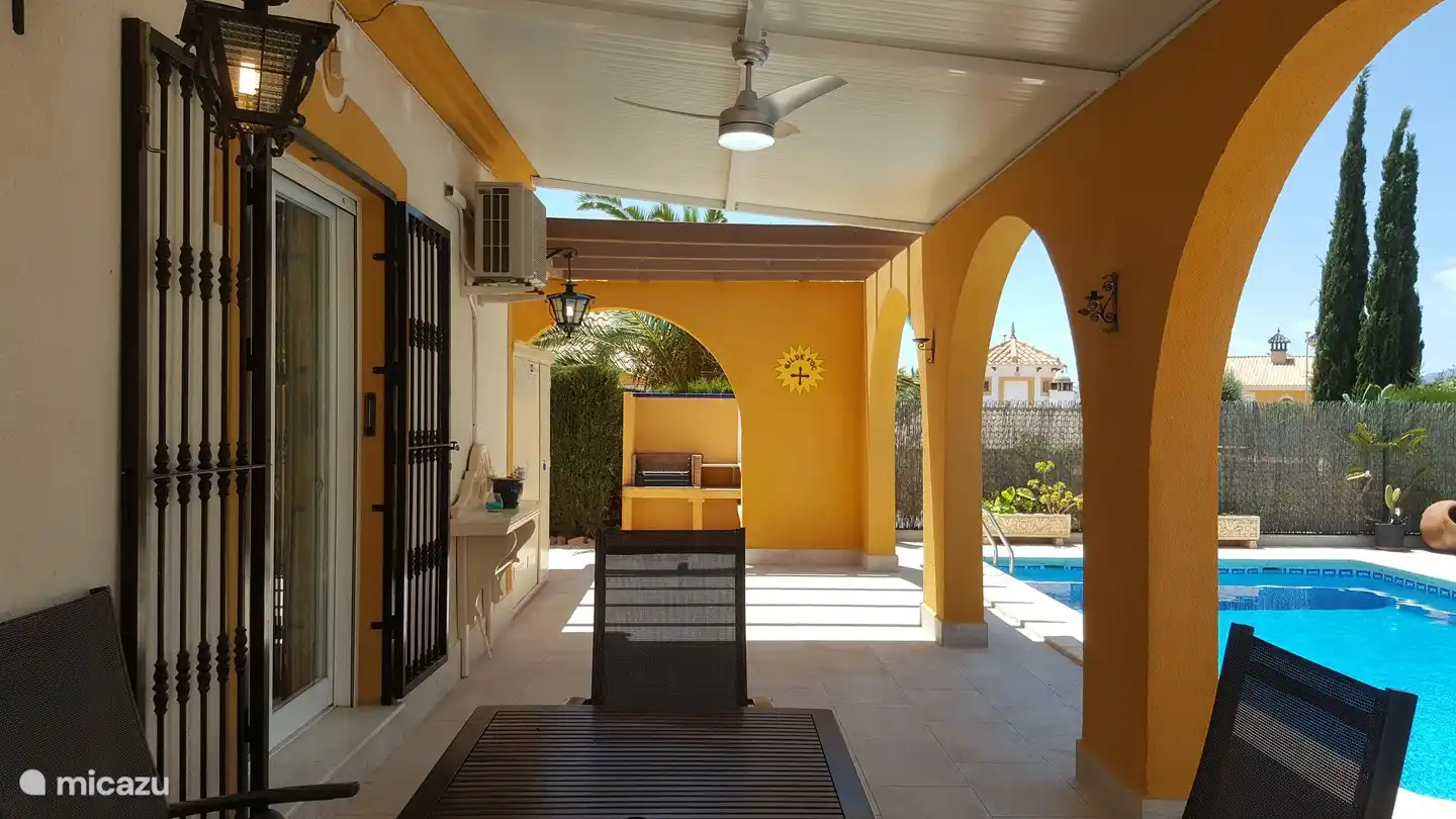 Behind the house, next to the (partially) covered terrace, is the private swimming pool [size 8 x 4 m]. Access via roman walk-in stairs, at the bottom you stand in water of ±105cm, at the end the pool is 1.8 m deep. A patio fan has been installed.  In the background you can see the outdoor kitchen with bbq.