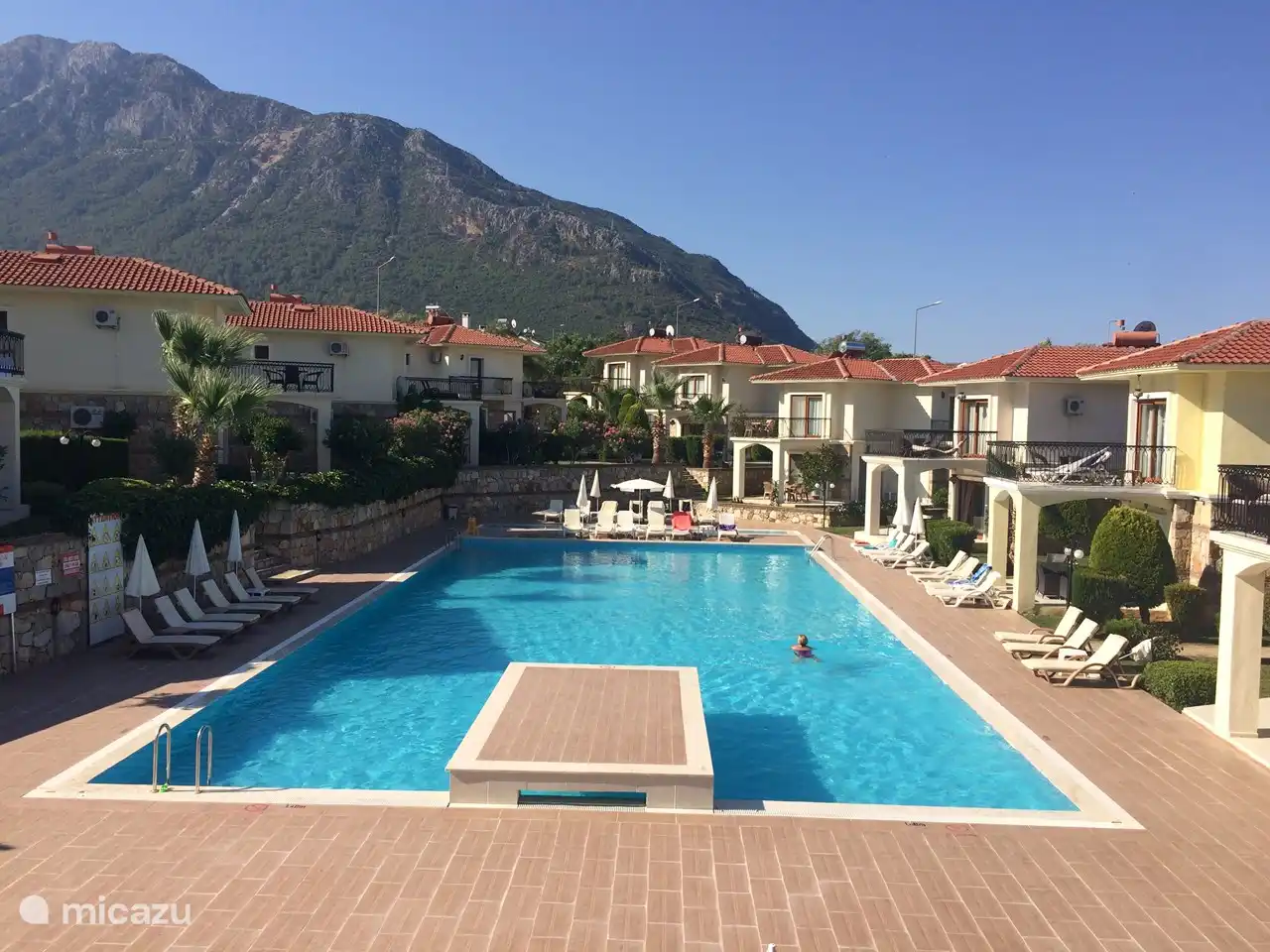 Vanaf het dakterras op de 1e etage is dit het uitzicht over het zwembad met in de verte de Babadag waar de hele dag de paragliders vanaf zweven.