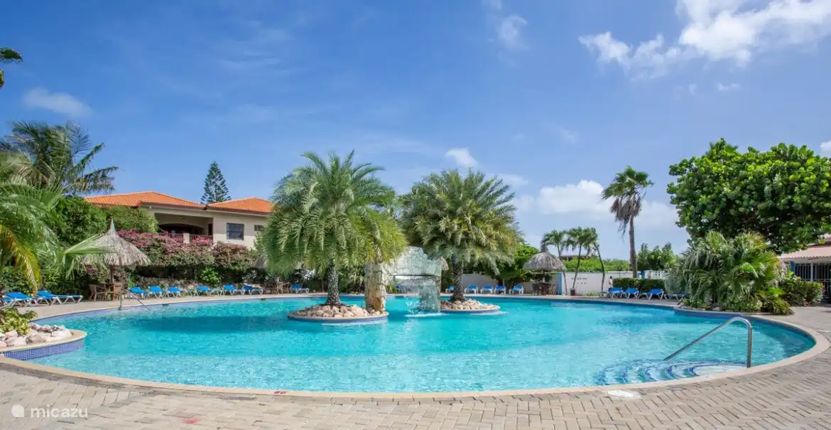 La preciosa piscina con muchas tumbonas y una piscina infantil para los más pequeños