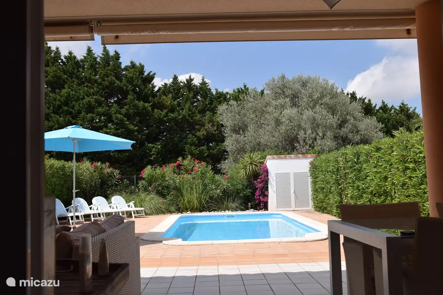El patio trasero con la piscina privada, visto desde la terraza cubierta