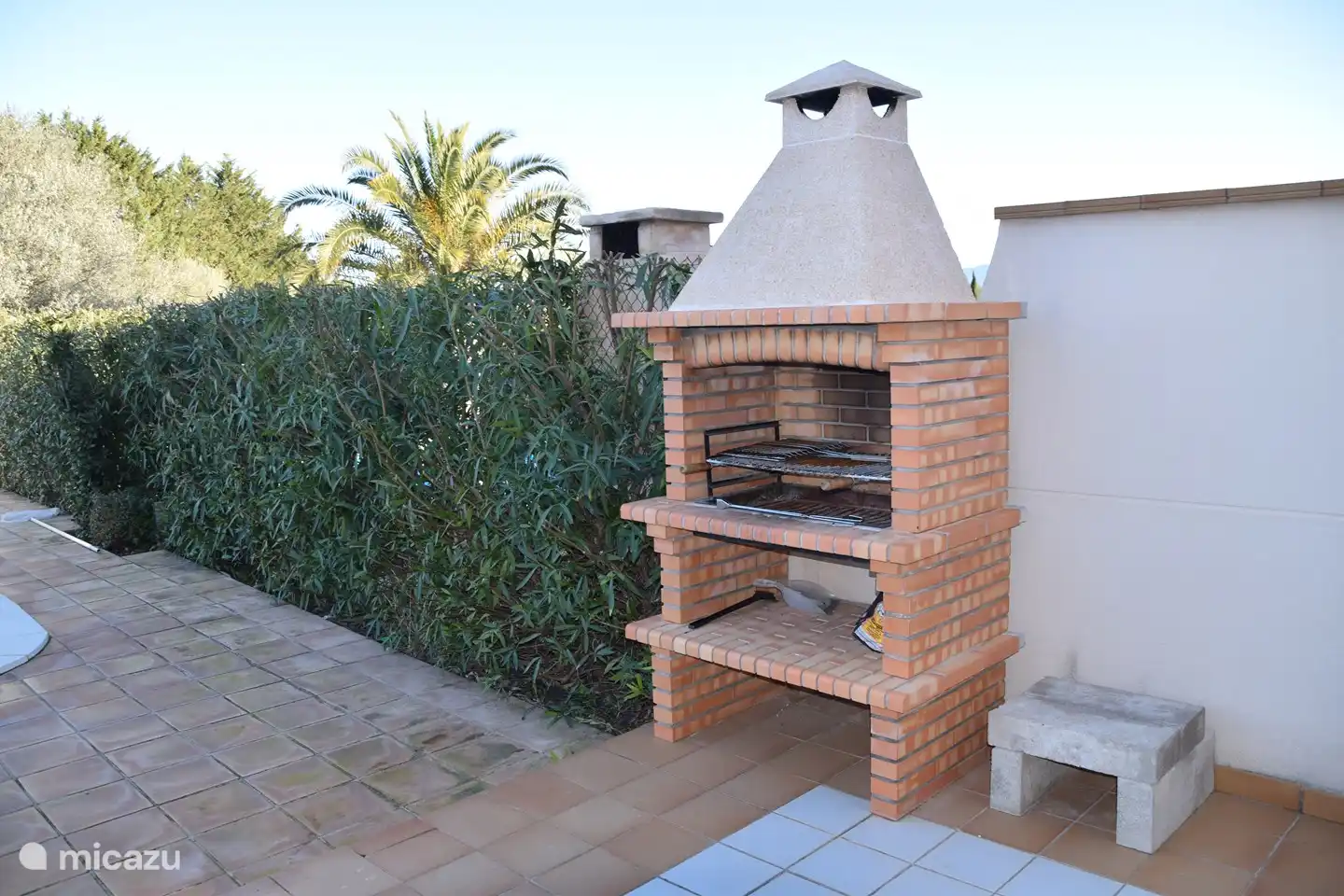 Gran barbacoa de piedra, situada en la terraza trasera junto a la piscina.
