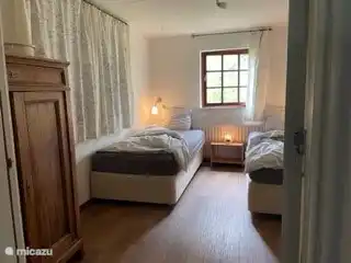 Schlafzimmer 2 (12 m2) mit zwei Boxspringbetten, Waschbecken und einem antiken Schrank mit Regalen.