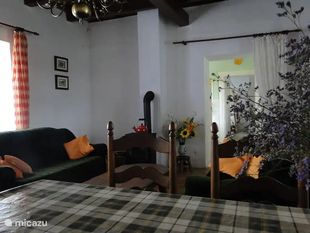 Blick vom Esszimmer auf das Wohnzimmer, im Hintergrund die Sofas und der Ofen, neben dem Wohnzimmer die Küche und das Schlafzimmer mit dem 'Master Bedroom'.