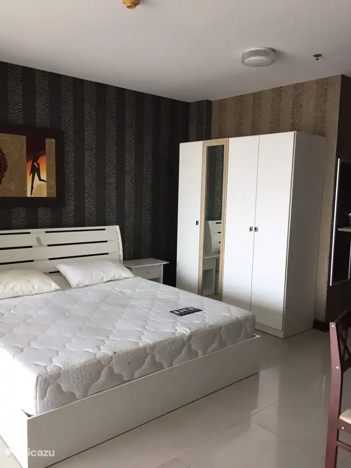 Ein wunderschöner, weiß glänzender Kleiderschrank neben dem Kingsize-Bett von 180 x 200 cm