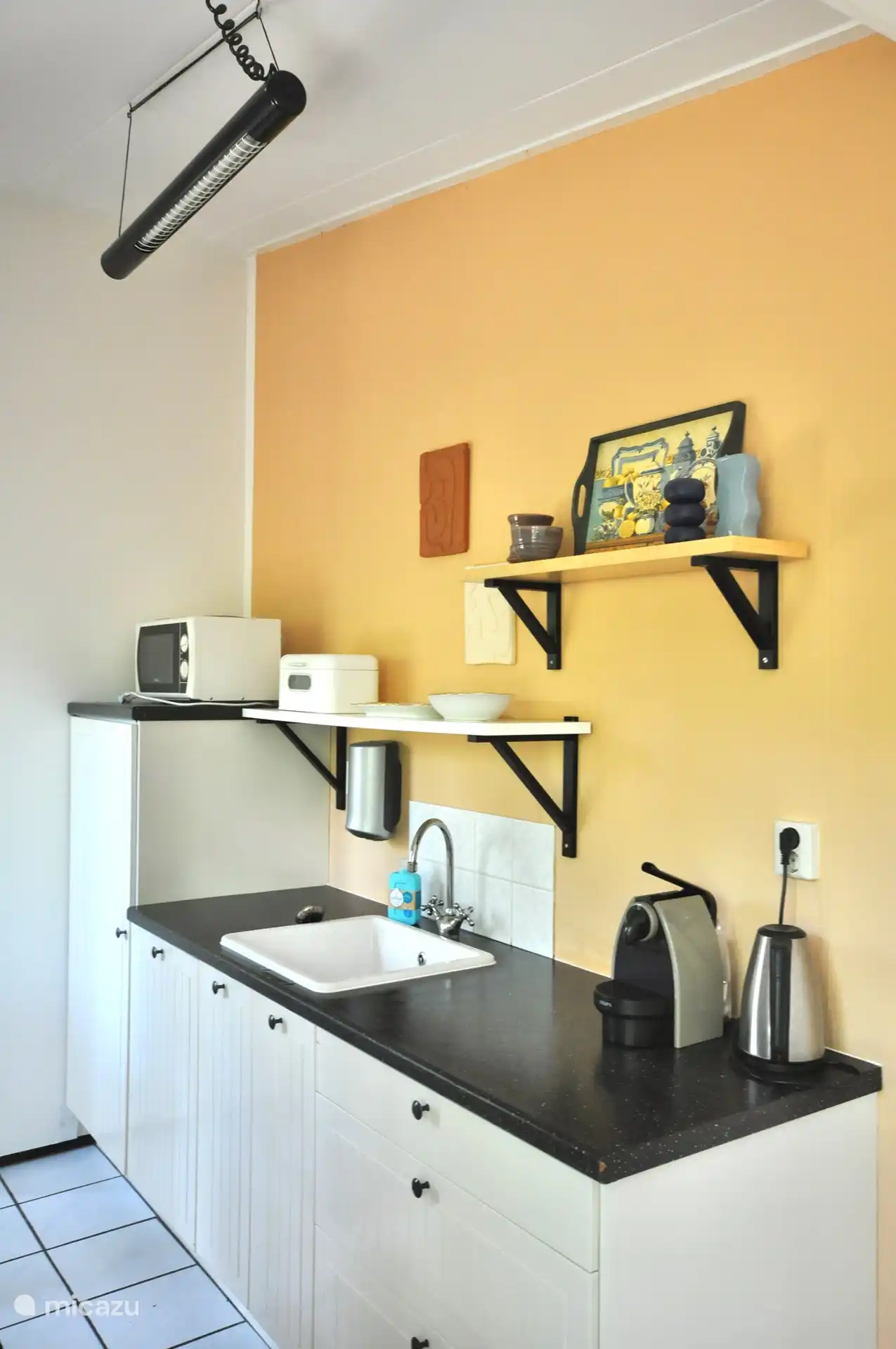 Auf der anderen Seite der Küche befinden sich ein Kühlschrank und eine Mikrowelle.