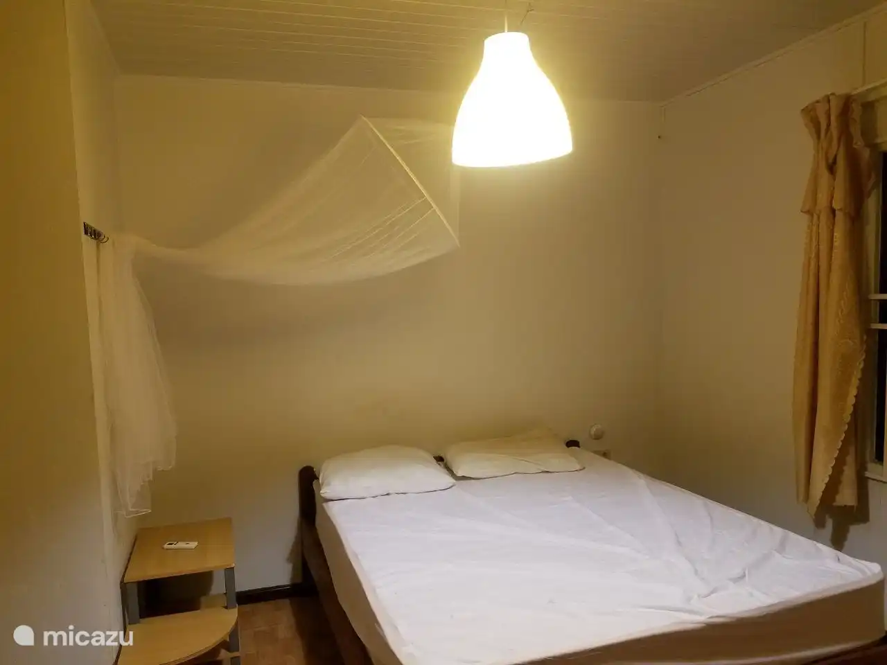 lit double dans la chambre du rez-de-chaussée avec moustiquaire